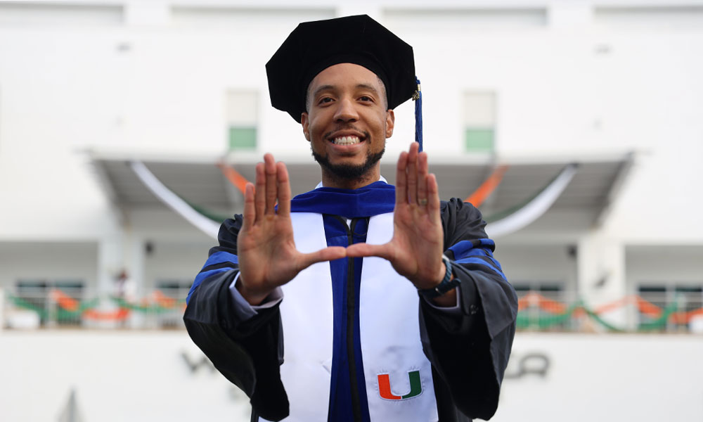 Alumni at graduation doing U sign