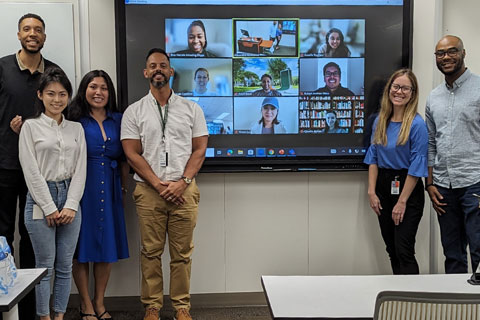 Group members of EJC standing together in front of a video conference call